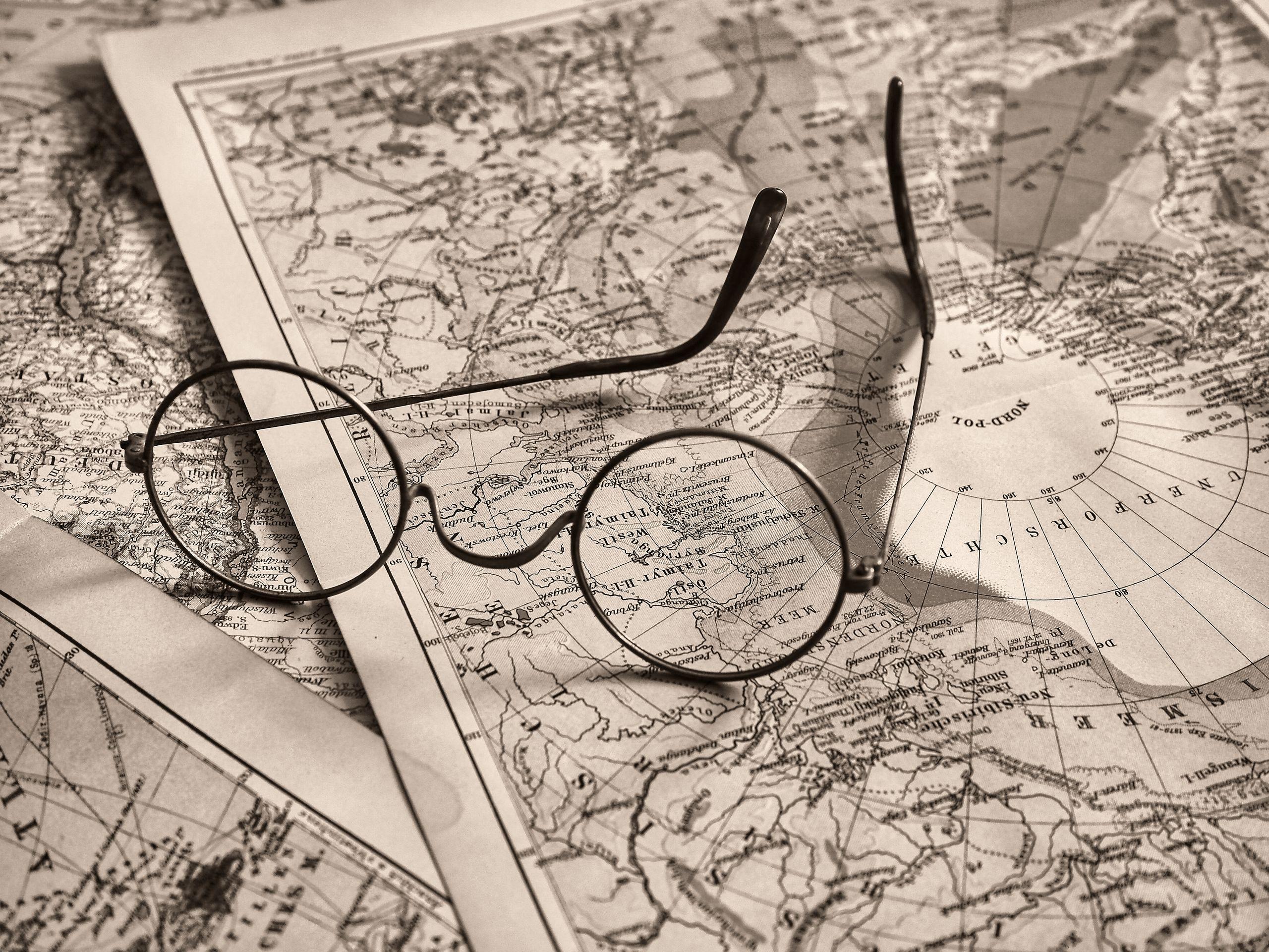 Round eyeglasses rest on an antique world map, evoking a sense of exploration.